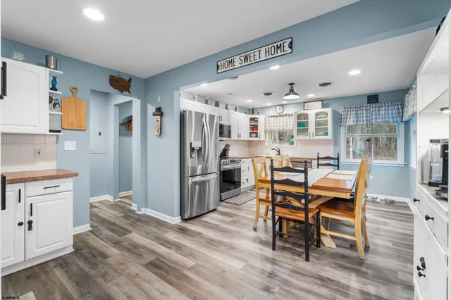 a dining hall with stainless steel appliances kitchen island granite countertop a table chairs and a refrigerator