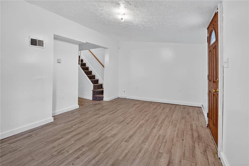 417 Alexander Street McKees Rocks, PA 15136 - Photo 6 of 21 a view of an empty room with wooden floor and stairs
