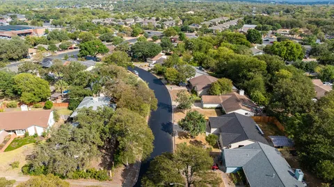 an aerial view of residential houses with outdoor space and trees