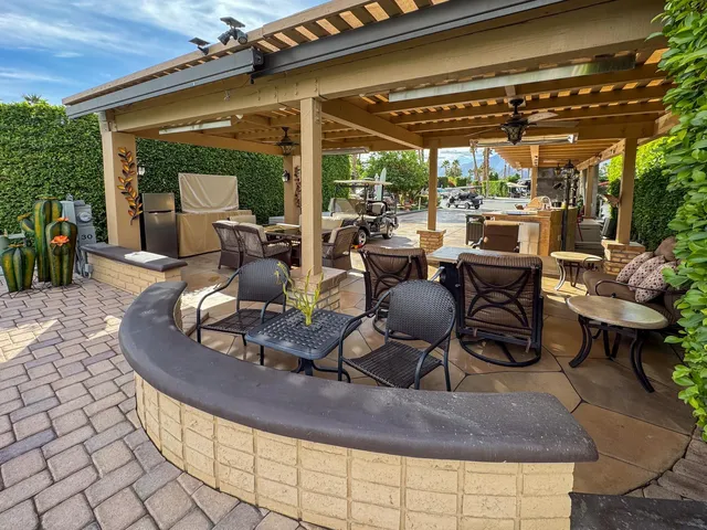 a view of a patio with table and chairs potted plants and floor to ceiling window