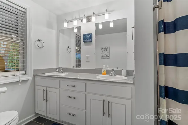 a bathroom with a granite countertop sink a toilet a mirror and shower