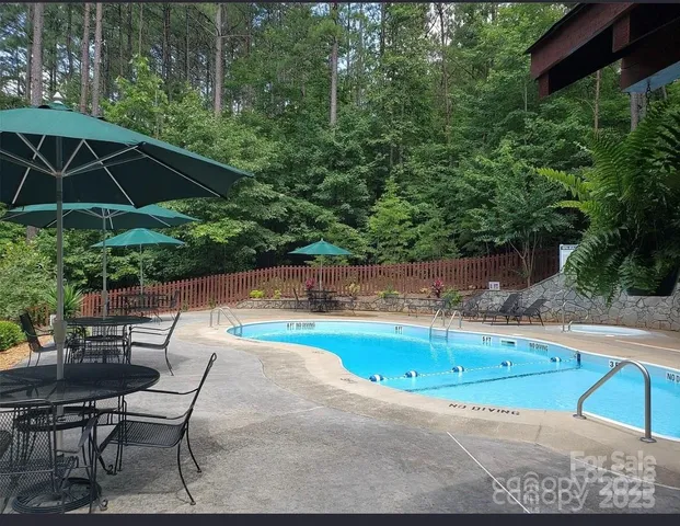 a backyard of a house with table and chairs under an umbrella
