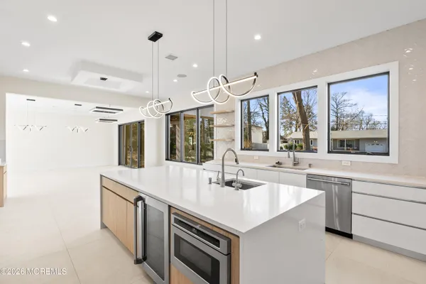 a large kitchen with stainless steel appliances a large counter top a sink a stove a refrigerator and a window