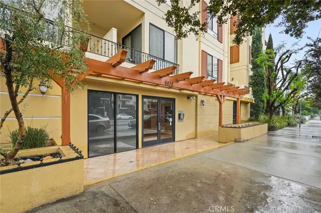 a front view of a building with a garden and trees