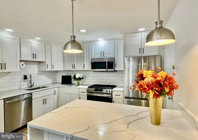 a kitchen with kitchen island granite countertop a sink a counter top space appliances and cabinets