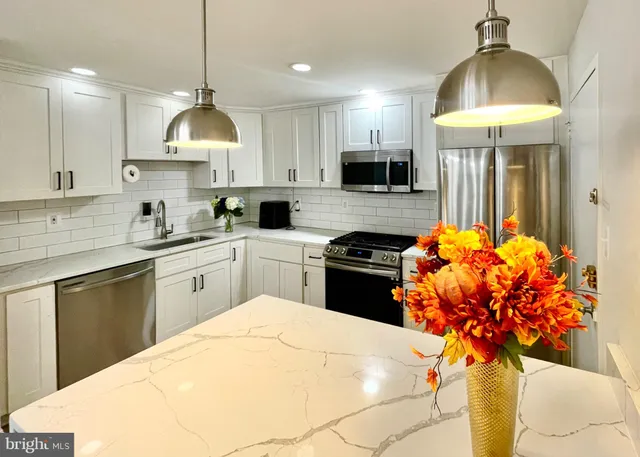 a kitchen with stainless steel appliances a white table chairs and a refrigerator