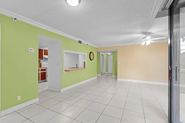 a view of an empty room with window and a kitchen