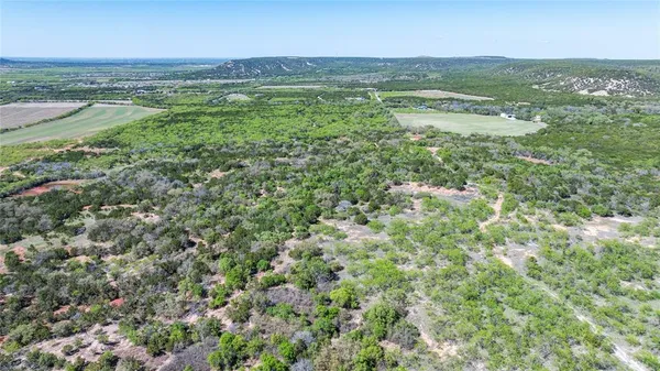 an aerial view of residential houses with outdoor space and trees