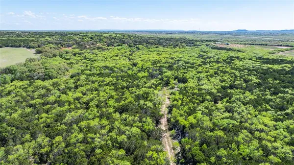 an aerial view of a houses with a yard and mountain view