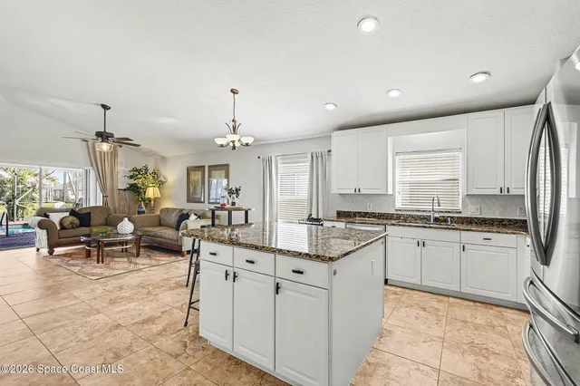 an open kitchen with granite countertop a sink and white cabinets