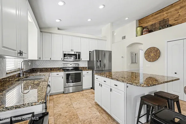 a kitchen with granite countertop a sink stove and refrigerator