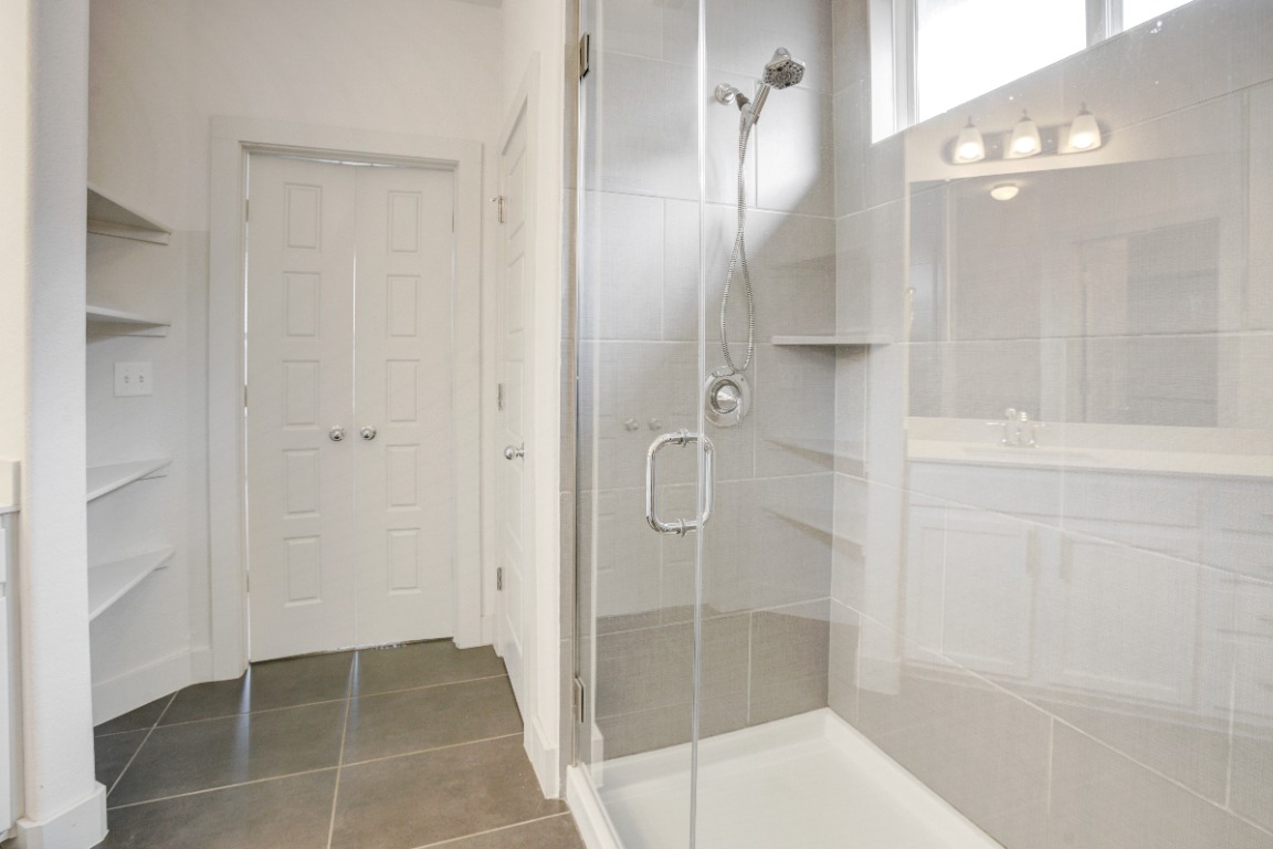 5910 Rubicon Run Austin, TX 78745 - Photo 16 of 18 Full bathroom featuring a shower stall, dark tile patterned floors, vanity, and a closet