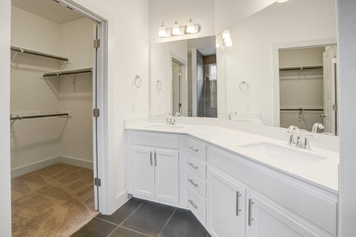 5910 Rubicon Run Austin, TX 78745 - Photo 8 of 18 Bathroom featuring a spacious closet, double vanity, dark tile patterned floors, and dark colored carpet