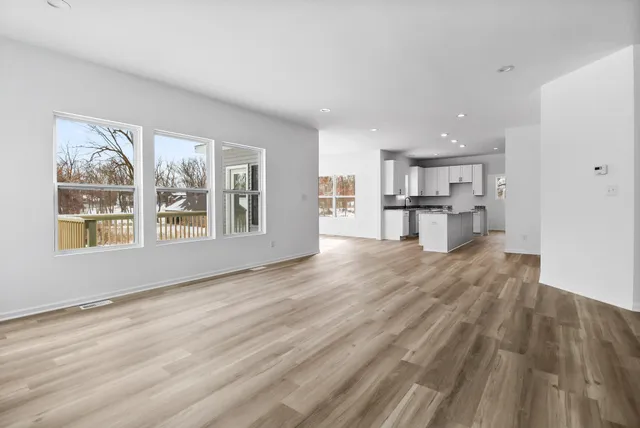 a view of empty room with kitchen and window