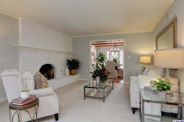 a living room with furniture a fireplace and potted plants