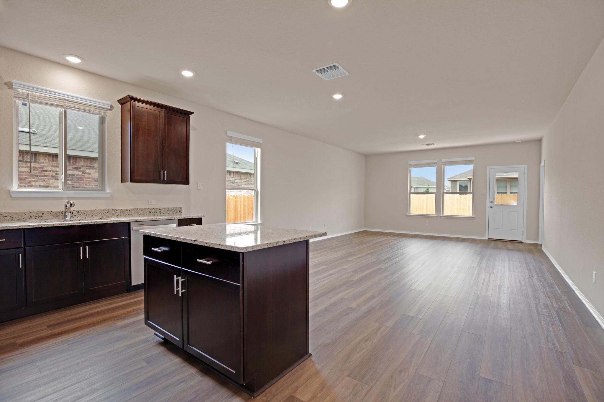 200 Janice Road Taylor, TX 76574 - Photo 7 of 25 An open-concept living area boasts a modern kitchen island and seamless flooring, connecting to an outdoor space.