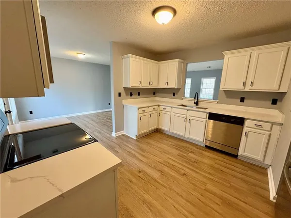 a kitchen with stainless steel appliances granite countertop a stove top oven a sink dishwasher and a microwave oven with wooden floor