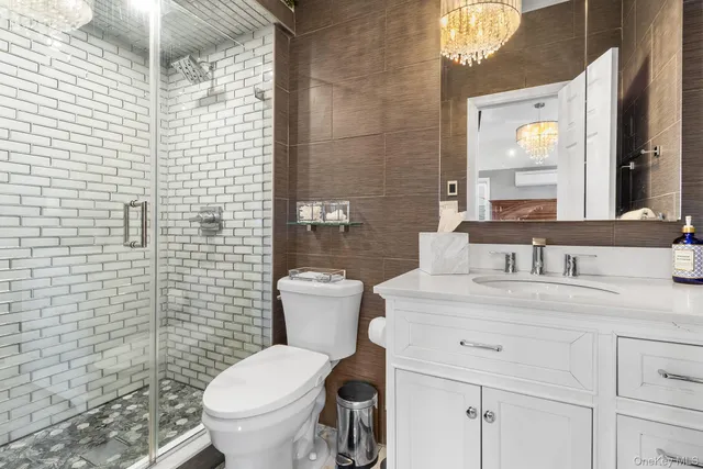 a bathroom with a granite countertop toilet a sink a mirror and shower