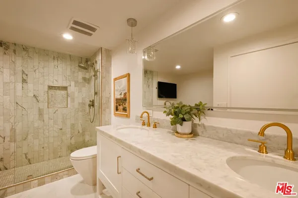 a bathroom with double vanity a toilet a sink and shower