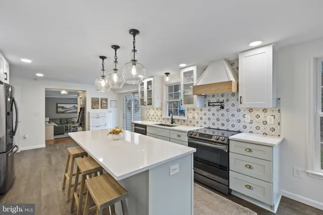 a kitchen with stainless steel appliances a stove a sink dishwasher and a refrigerator with wooden floor