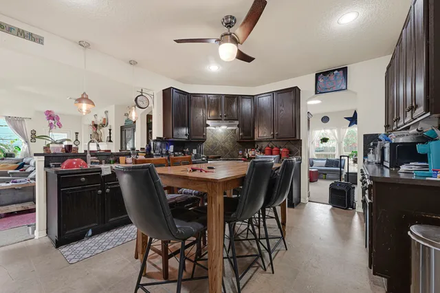 a kitchen with stainless steel appliances kitchen island granite countertop a dining table chairs refrigerator and sink