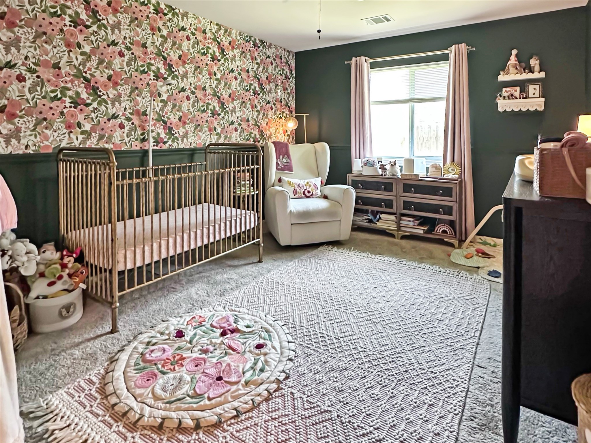 20213 Kearney Hill Road Pflugerville, TX 78660 - Photo 18 of 27 A charming nursery features floral accent wall, plush carpeting, and elegant window treatments.