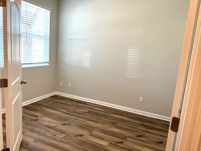 a view of an empty room with wooden floor and a window