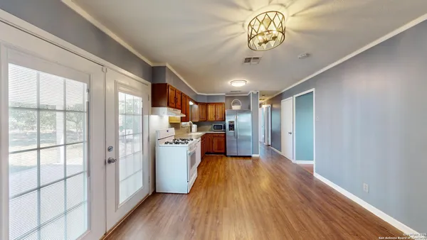 a view of a kitchen with a refrigerator wooden floor and a ceiling fan