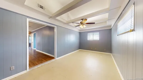 a view of an empty room with windows and chandelier fan