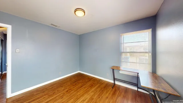 an empty room with wooden floor and windows