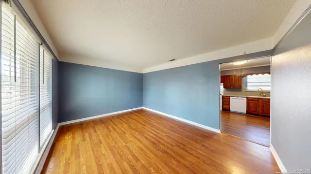 a view of a room with wooden floor and a kitchen