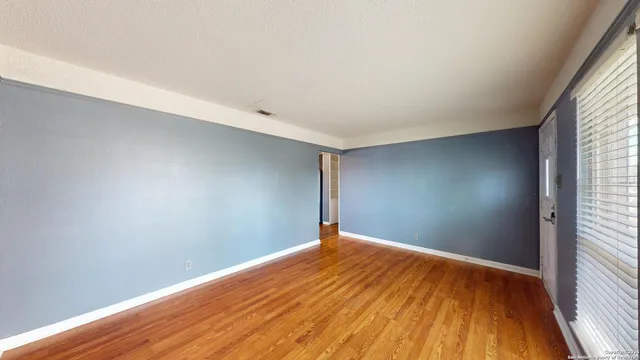 a view of empty room with wooden floor