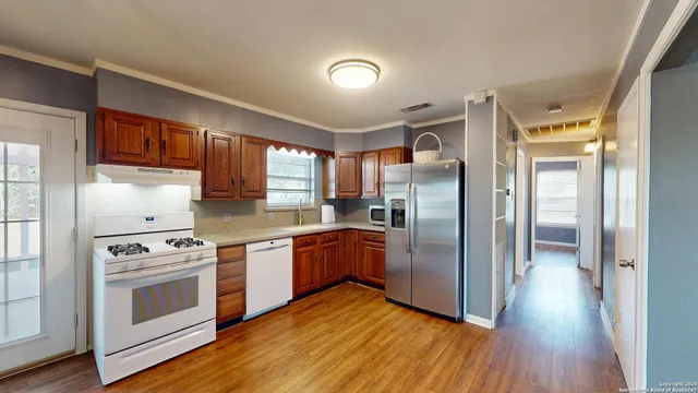 a kitchen with stainless steel appliances granite countertop a refrigerator a stove and a sink