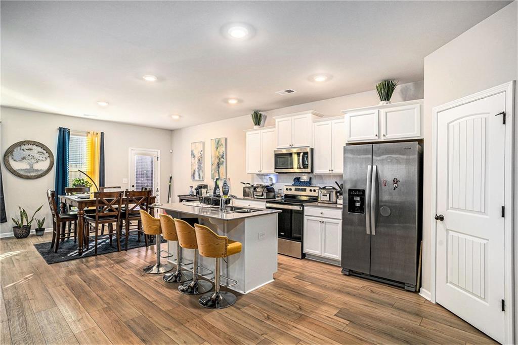 11940 Brightside Parkway Hampton, GA 30228 - Photo 12 of 31 a kitchen with stainless steel appliances granite countertop a refrigerator a stove top oven a dining table and chairs with wooden floor