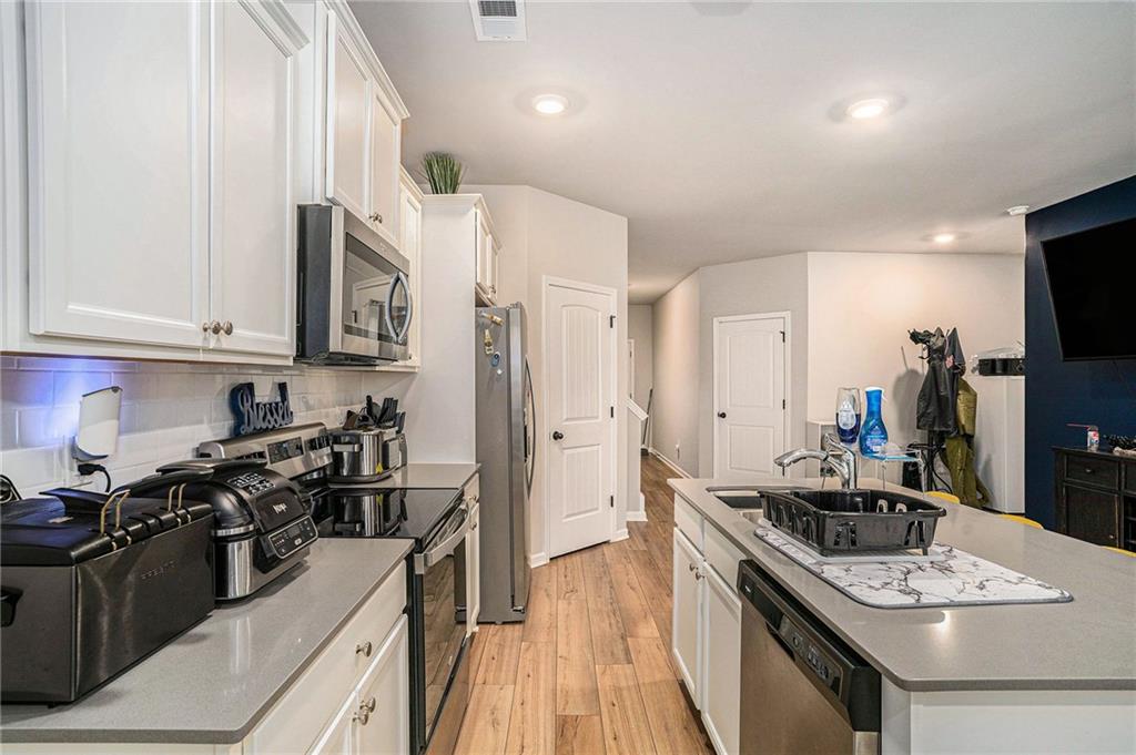 11940 Brightside Parkway Hampton, GA 30228 - Photo 13 of 31 a kitchen with stainless steel appliances granite countertop a stove top oven a sink dishwasher and a refrigerator with wooden floor