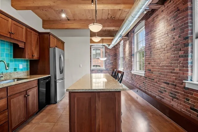 a kitchen with stainless steel appliances granite countertop a refrigerator a sink dishwasher a stove and white countertops with wooden floor