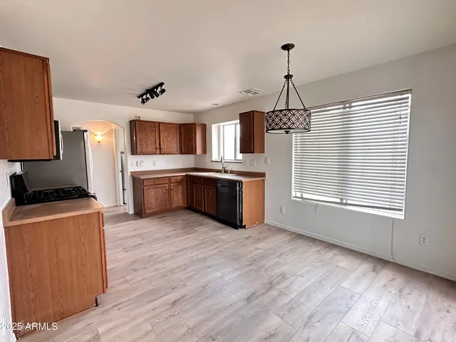 a kitchen with stainless steel appliances granite countertop a stove a sink dishwasher a refrigerator and a oven with wooden floor