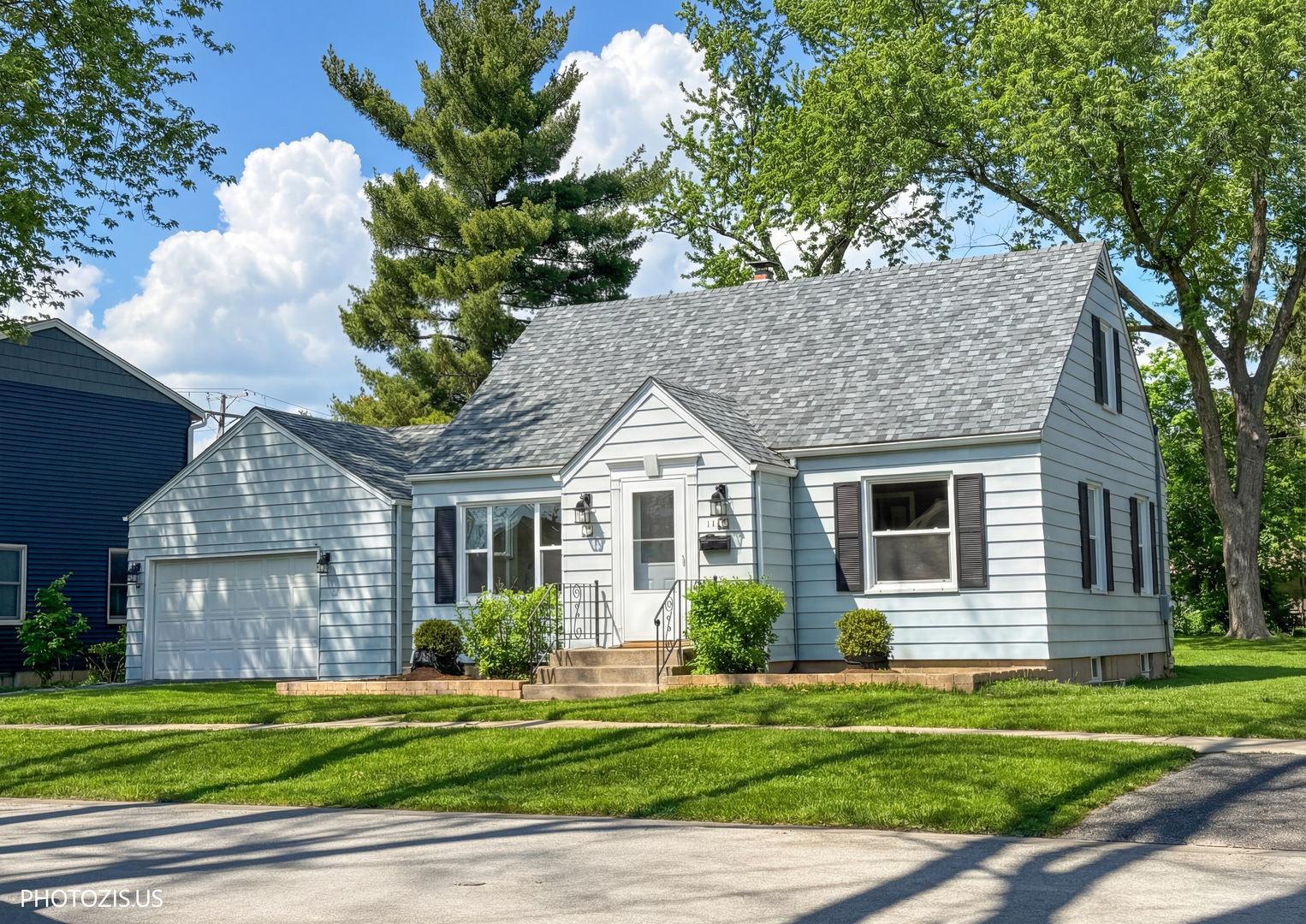 a front view of a house with a garden and trees