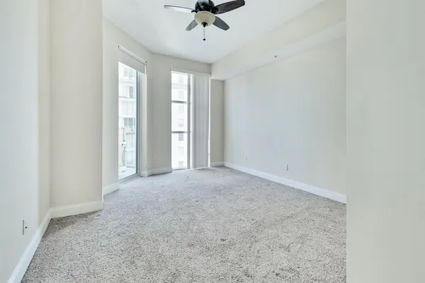 an empty room with a ceiling fan and window