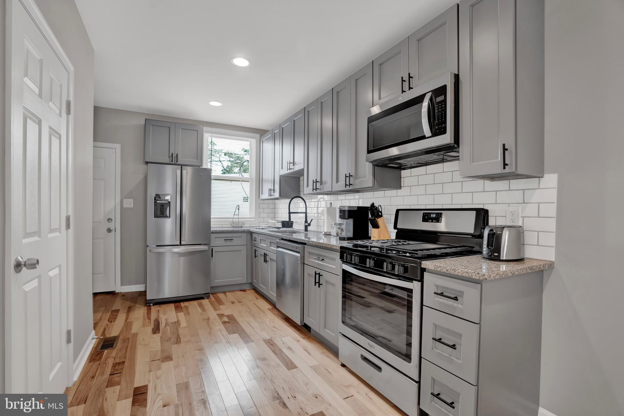 2111 East Chase Street Baltimore, MD 21213 - Photo 7 of 19 a kitchen with stainless steel appliances a refrigerator stove and microwave