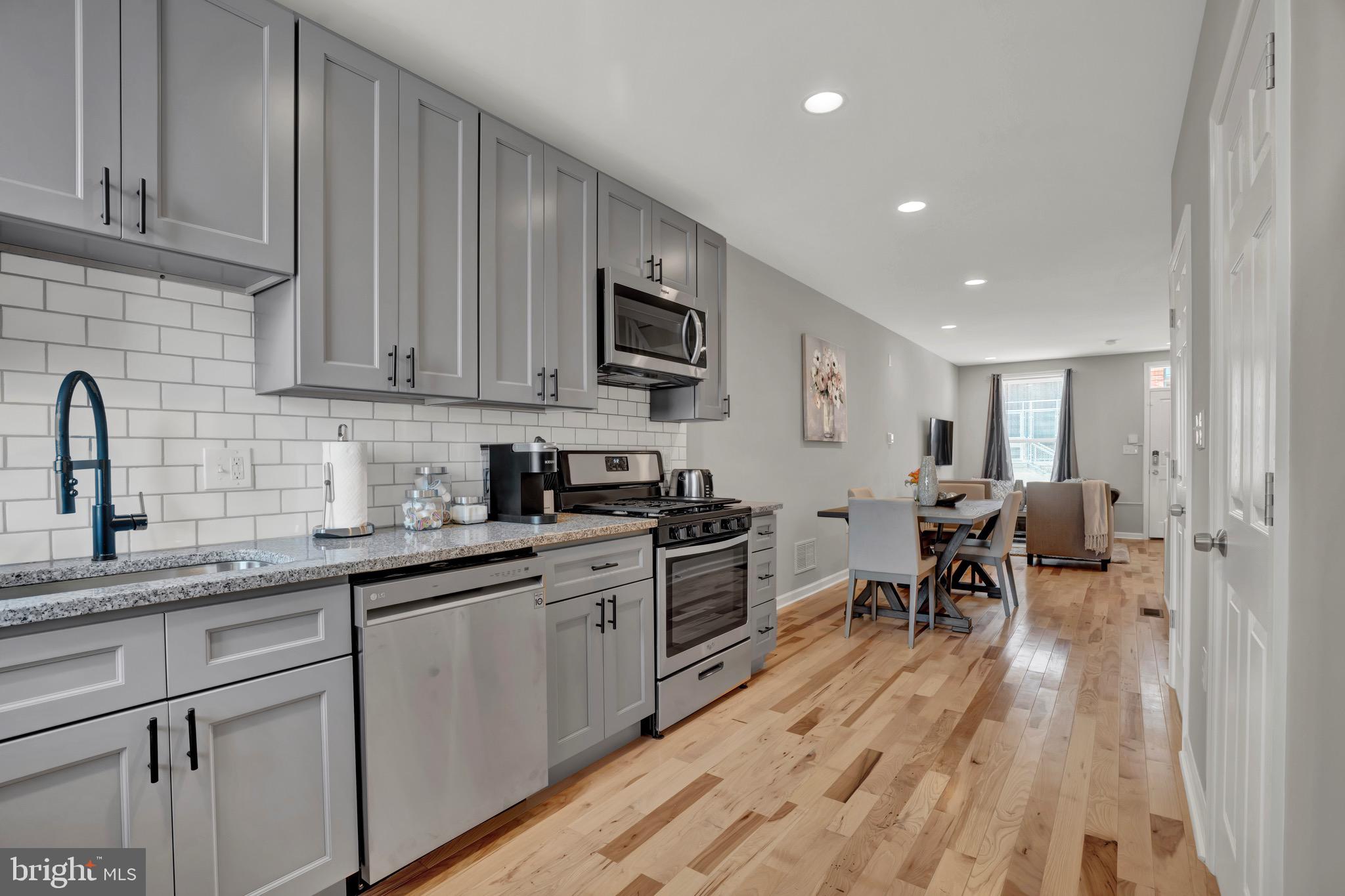 2111 East Chase Street Baltimore, MD 21213 - Photo 8 of 19 a kitchen with sink cabinets and wooden floor