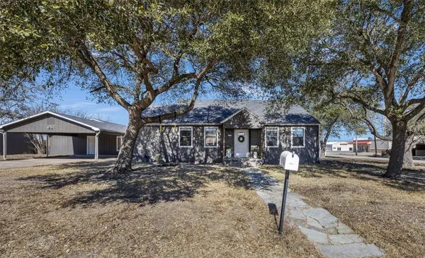 a front view of a house with a yard and large tree