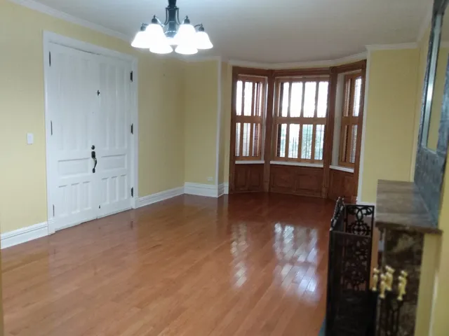 a view of an empty room with window and wooden floor