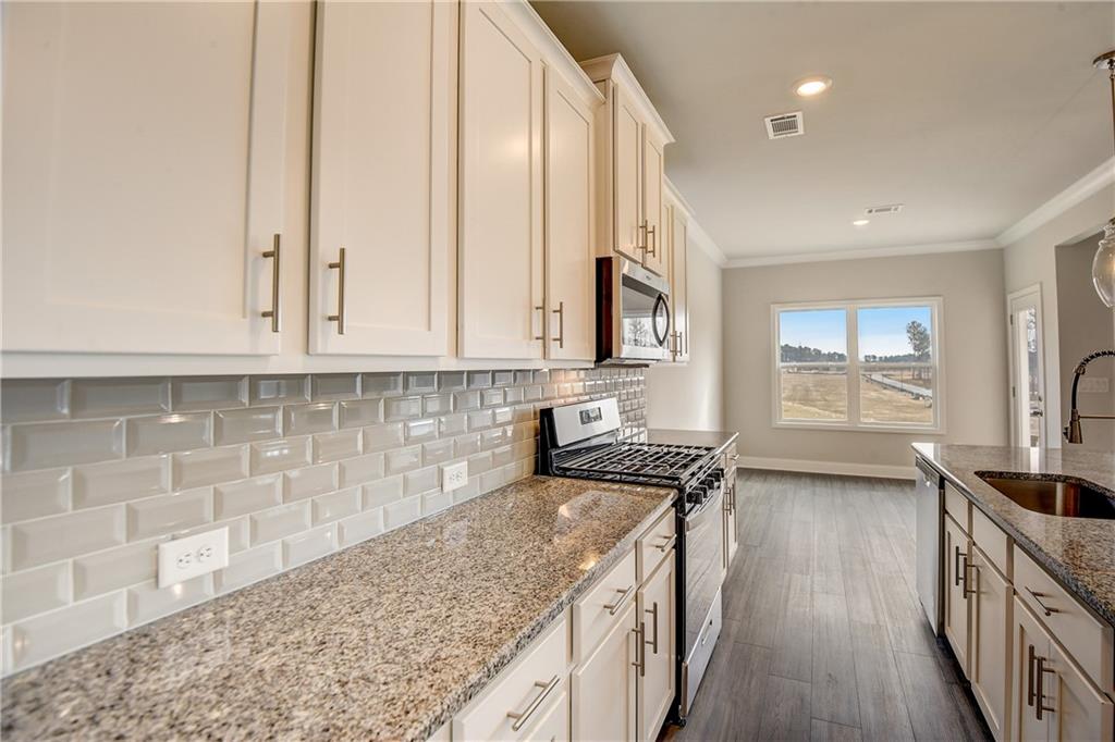 255 Wingate Drive Winder, GA 30680 - Photo 14 of 76 a kitchen with stainless steel appliances granite countertop a stove a sink and a white cabinets