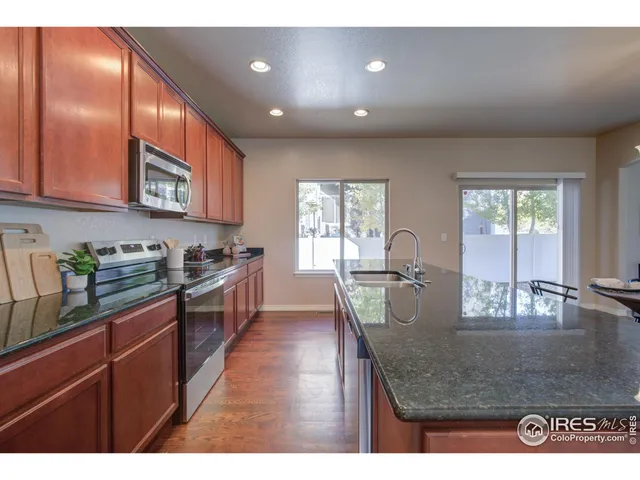 a dining hall with stainless steel appliances kitchen island a table and chairs in it