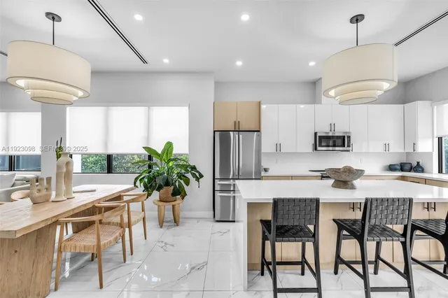 a kitchen with stainless steel appliances kitchen island granite countertop a stove a sink a dining table and chairs