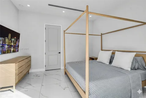 a spacious bedroom with a bed and a flat screen tv