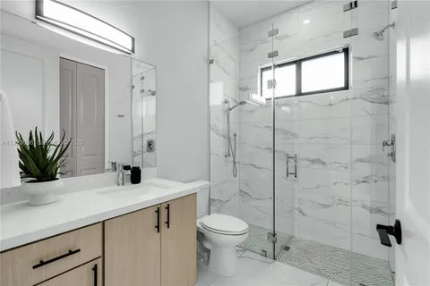 a bathroom with a granite countertop sink a toilet and shower