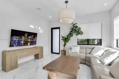 a living room with furniture a chandelier and a flat screen tv