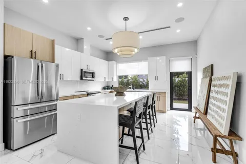 a kitchen with stainless steel appliances a refrigerator a stove a sink a dining table and chairs with wooden floor